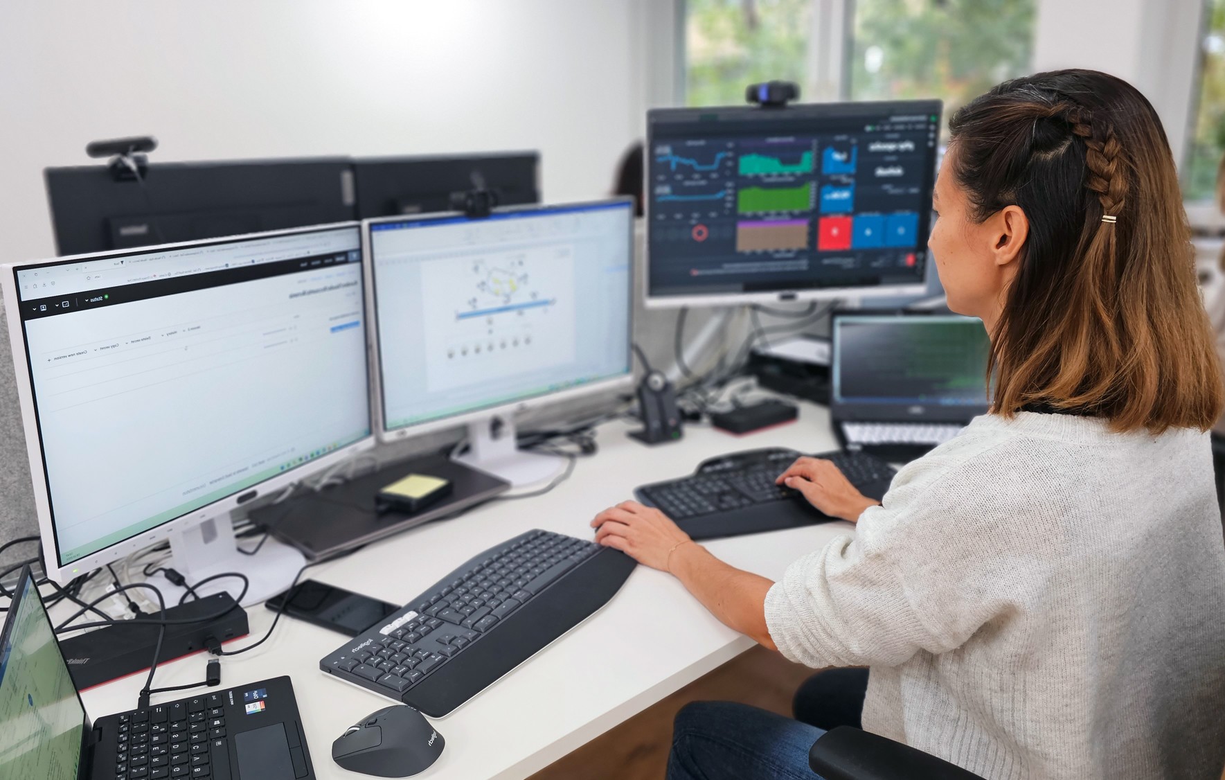 Eine Mitarbeiterin aus der Entwicklung bei Ihrer Arbeit mit 3 Bildschirmen in unserem Büro.
